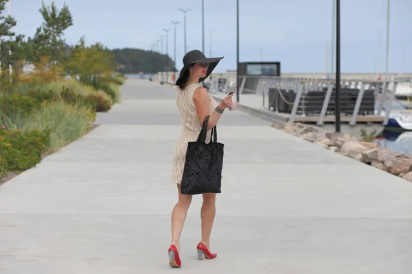 가방을 들고 고개를 들고 거리를 걷는 여자 — 스톡 사진