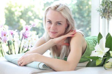 Çekici ve gülümseyen bir kadın masaj paspasında yatıyor.