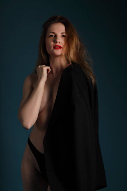 Siyah arka planda poz veren, ceketli şık genç bir kadın.