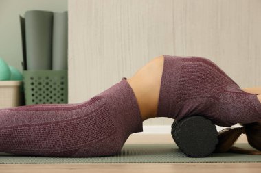 Baldır kaslarına köpük silindirle masaj yapan bir kadının yakın çekimi..