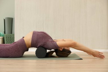 Baldır kaslarına köpük silindirle masaj yapan bir kadının yakın çekimi..