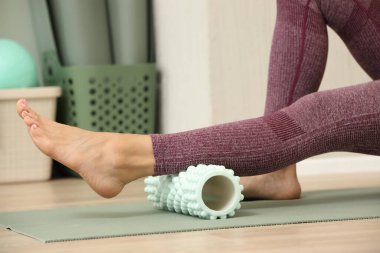 Baldır kaslarına köpük silindirle masaj yapan bir kadının yakın çekimi..