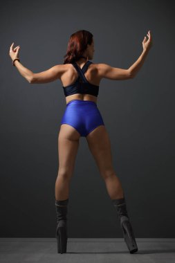 Atletik kıyafetli güçlü bir kadın içeride güçlü bir poz veriyor.