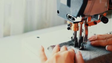 Endüstriyel düz dikiş makinesine dikiş atan bir kadın..