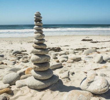 Stacked stones on a sandy beach by the Ocean. clipart