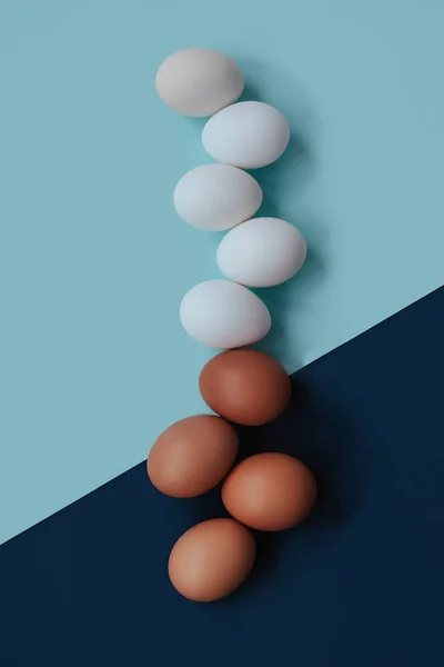 Beyaz ve kırmızı yumurtalar mavi bir masada yatıyor.. — Stok fotoğraf