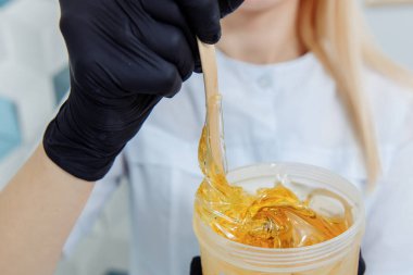 Tahta bir spatula kavanozdan altın doğal balmumu alır.. 