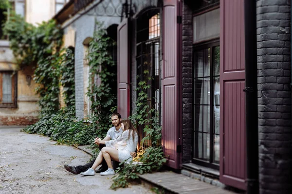 Bir adam ve bir kız tahta pencere eşiğinde oturur ve sarılırlar..