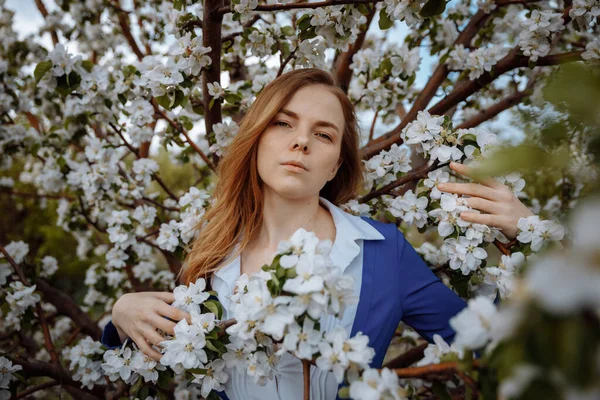 Une jeune femme européenne entourée de grandes fleurs blanches regarde dans le cadre. — Photo