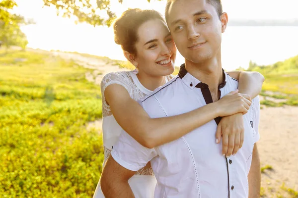 Eine junge Frau umarmt einen Mann und lächelt breit. Junge Leute sind weiß gekleidet. — Stockfoto