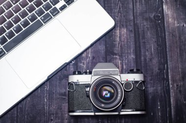 Ahşap arka planda dizüstü bilgisayar ve fotoğraf makinesi