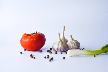 Beyaz bir zemin üzerinde sarımsak ve domates.