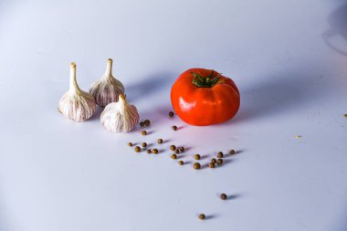 Beyaz bir zemin üzerinde sarımsak ve domates.
