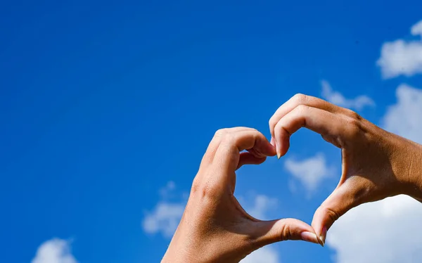 Heart symbol from hands on the blue sky background, Concept for Love or Health.