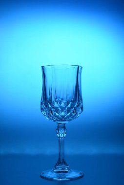 Arka planda şarap kadehi var. İyi kristal cam konsepti. Dikey, mavi tonlu