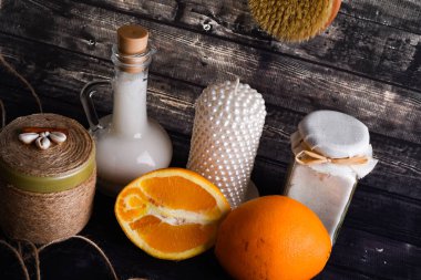 Vücut bakım ürünleri ve koyu ahşap arkaplan üzerine yazı için alan içeren döşeme bileşimi. Bir kavanoz doğal krema, bir şişe hindistan cevizi yağı ve olgun bir portakal ve mum.