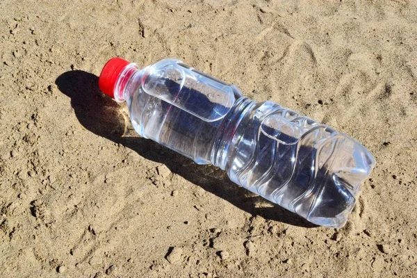 water bottle on the beach. thirst on a hot summer Sunny day.