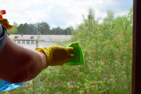 home cleaning window washing men\'s hand with a rag washes the window with drops of detergent, close-up, soft focus