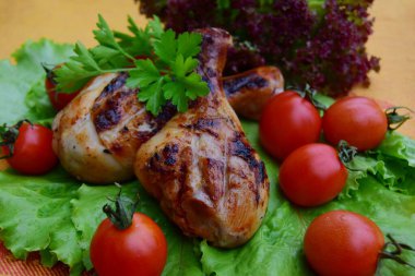 Kırmızı domatesli kızarmış tavuk bacağı ve yeşil marul yaprakları. Zararlı beslenme kavramı