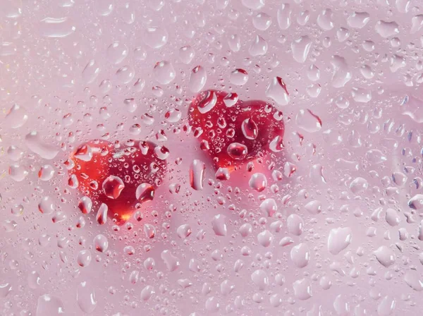 Aşk kavramı, su damlacıkları olan iki kırmızı kalp, açık arkaplanda soyut bir resim.