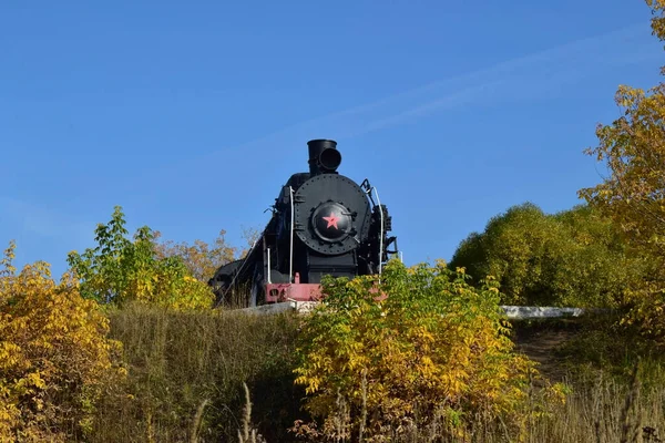 Eski bir buharlı lokomotif köy istasyonundan ayrılıyor. Sonbahar dekorunda buhar lokomotifi, ön manzara — Stok fotoğraf