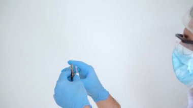 Kişisel koruma ekipmanlarında çalışan bir doktor aşı ampullerini inceleyip uzayı kopyalıyor.