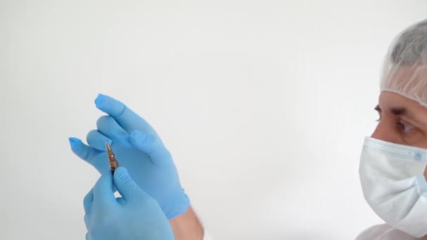 Doutor em uma máscara médica e luvas abre uma ampola de vacina, close-up, espaço de cópia — Vídeo de Stock