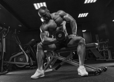 Yakışıklı ve kaslı bir adam, spor salonunda kameraya poz veriyor.