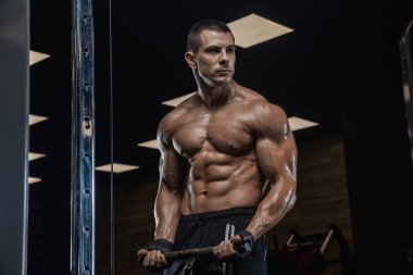 Bir genç yakışıklı vücut geliştirmeci salonunda bir egzersiz yapıyor.