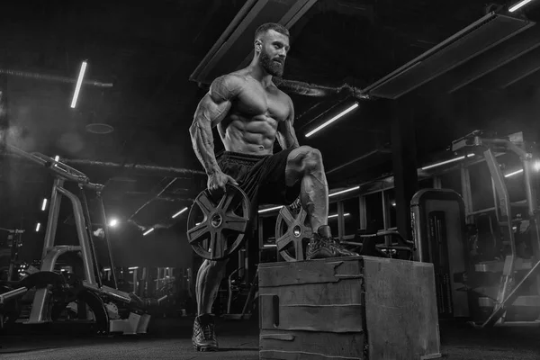 Çekici uzun kaslı vücut geliştirici. Moder fitness merkezinde ağırlık kaldırıyor..