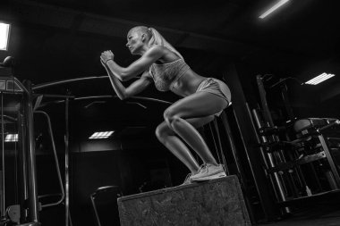 Zıplayan genç kadın kutusuna zıpla. Kadın sporcu spor salonunda kutu atlayışı yapıyor.