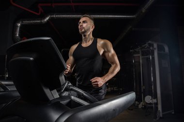 Kaslı vücut geliştirmeci adam spor salonunda dumbbells ile yapıyor