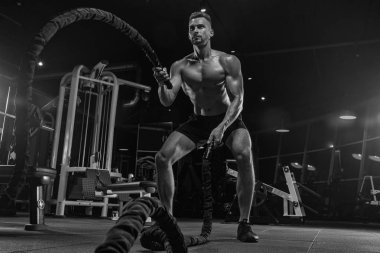 Kaslı vücut geliştirmeci adam spor salonunda dumbbells ile yapıyor