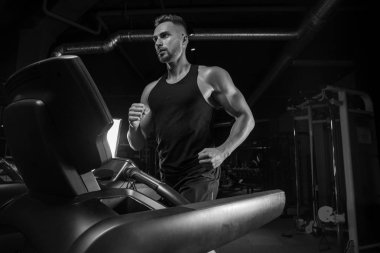 Kaslı vücut geliştirmeci adam spor salonunda dumbbells ile yapıyor