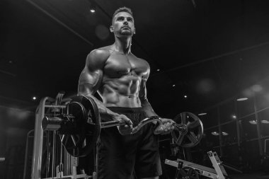 Kaslı vücut geliştirmeci adam spor salonunda dumbbells ile yapıyor