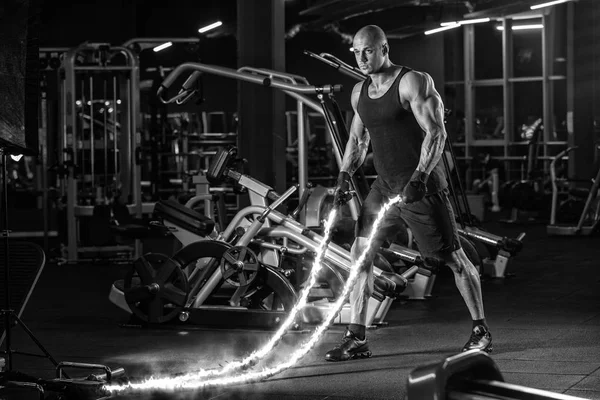 Men with battle rope battle ropes exercise in the fitness gym. CrossFit concept. gym, sport, rope, training, athlete, workout, exercises concept