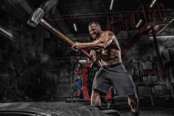 Sportlicher Fitness-Mann schlägt beim Schlittentraining mit Hammer auf Reifen ein — Stockfoto