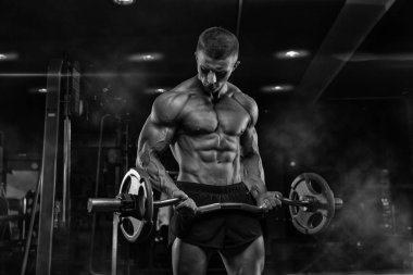 oung yetişkin vücut geliştirmeci spor salonunda ağırlık kaldırma yapıyor.