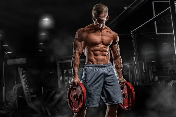 Joven atleta masculino culturista posando y haciendo ejercicios deportivos — Foto de Stock