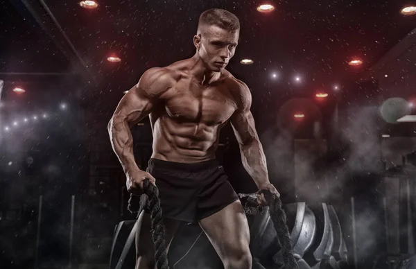 Atleta masculino fisiculturista posando em um fundo preto — Fotografia de Stock