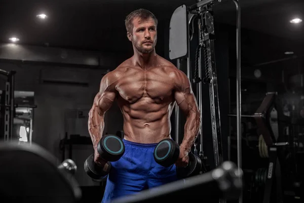 Bello uomo con grandi muscoli, in posa presso la fotocamera in palestra — Foto Stock