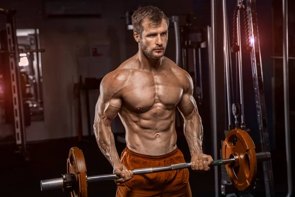 L'uomo tatuato senza maglietta sta sollevando pesi nel club sportivo. Lui è st — Foto Stock