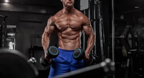 Bello uomo con grandi muscoli, in posa presso la fotocamera in palestra — Foto Stock