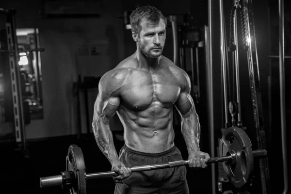 L'uomo tatuato senza maglietta sta sollevando pesi nel club sportivo. Lui è st — Foto Stock