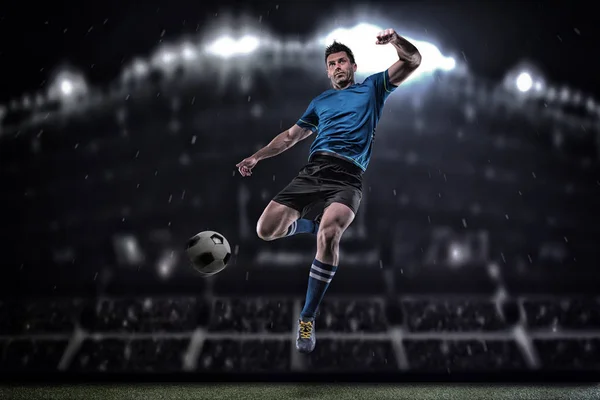 Voetballer in actie op een donkere achtergrond — Stockfoto