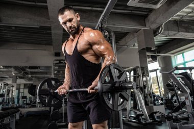 Çekici uzun kaslı vücut geliştirici. Moder fitness merkezinde ağırlık kaldırıyor..