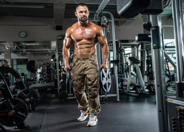 Çekici uzun kaslı vücut geliştirici. Moder fitness merkezinde ağırlık kaldırıyor..