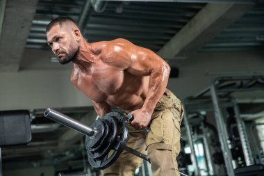 Çekici uzun kaslı vücut geliştirici. Moder fitness merkezinde ağırlık kaldırıyor..