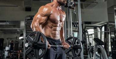 Çekici uzun kaslı vücut geliştirici. Moder fitness merkezinde ağırlık kaldırıyor..