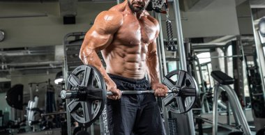 Çekici uzun kaslı vücut geliştirici. Moder fitness merkezinde ağırlık kaldırıyor..